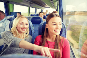 Zwei Schülerinnen schauen aus dem Reisebus und zeigen auf Sehenswürdigkeiten – Stadtrundfahrt Berlin für Schulklassen